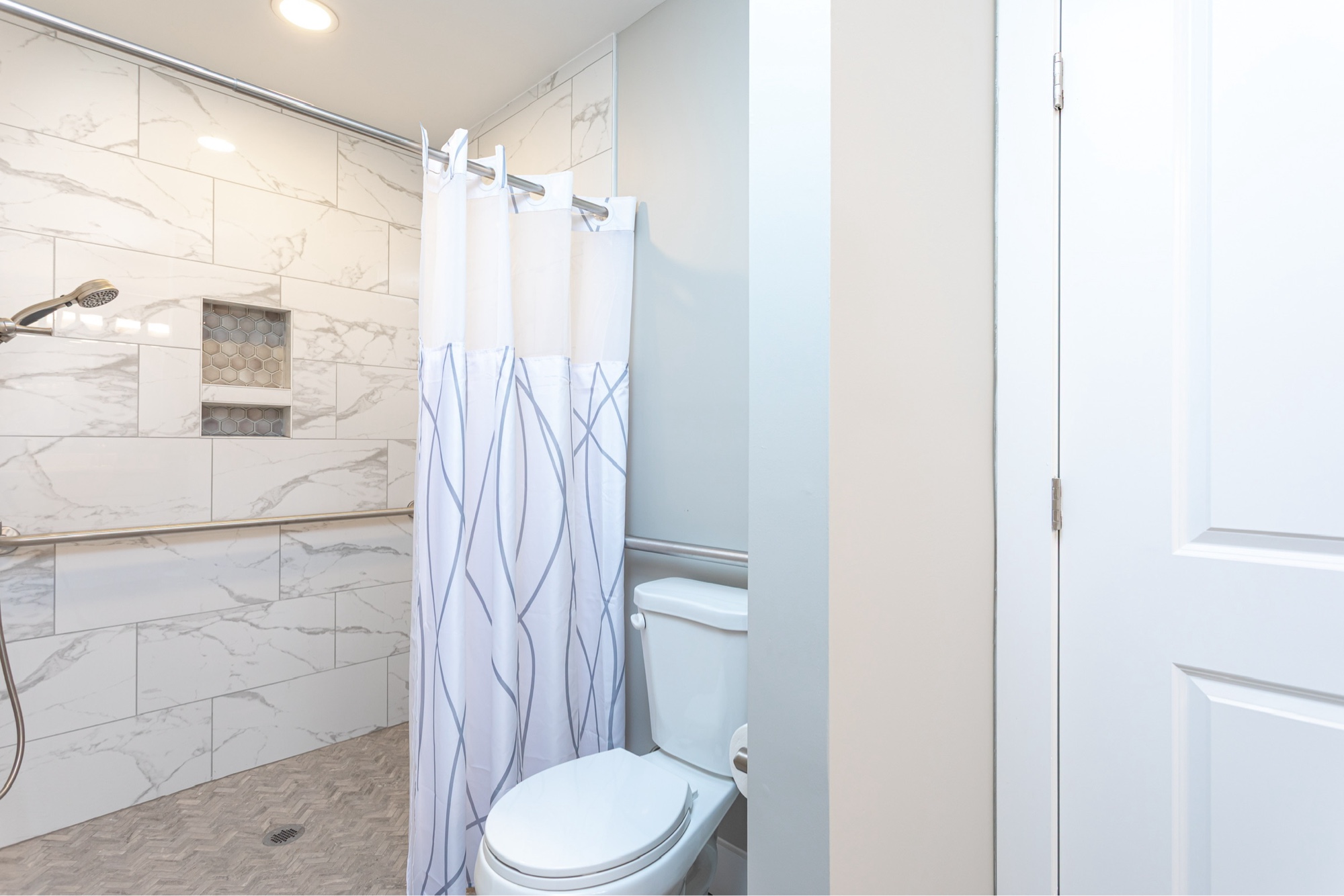 A tiled walk-in shower with grab bars and safety features